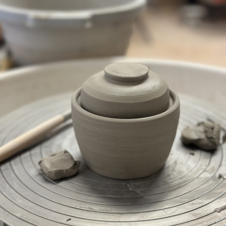 Kleine Keramiktöpfe, die auf einer Töpferscheibe gedreht wurden und nun zum Brennen bereit sind.