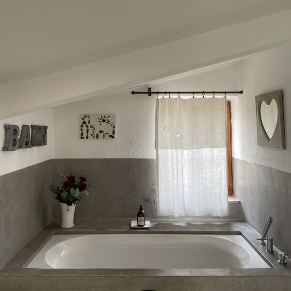 Stone bathtub in a rustic bathroom with curtain and decorations.