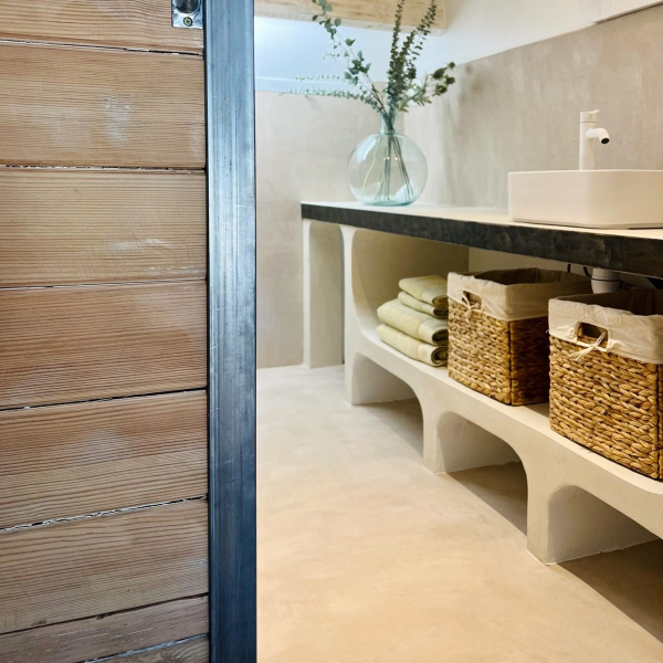 Rustic bathroom with a sink, wicker baskets and a plant.