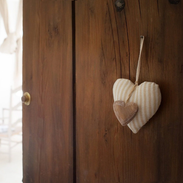 A felt heart hanging from a dark wooden door, leading into a bright and warm room.