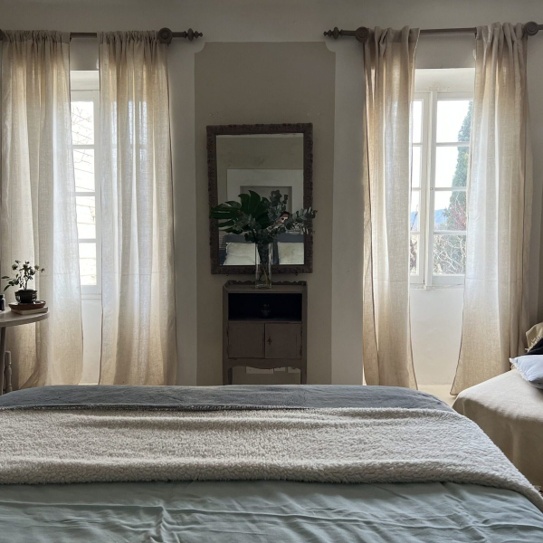 Cozy room with linen curtains, a mirror and comfortable bedding.