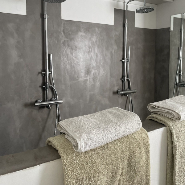 Modern shower with white towels and a textured grey and white wall.