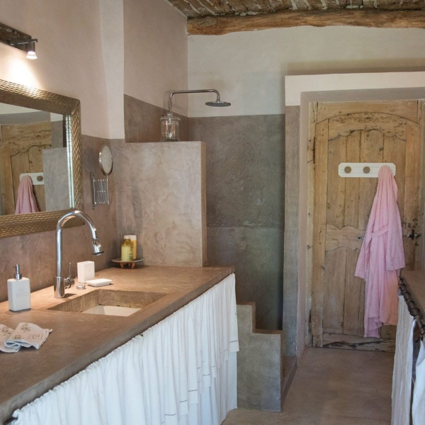 Rustikales Badezimmer mit Spiegel, Dusche und sichtbaren Holzelementen.