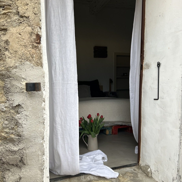 Eine Steintür öffnete sich zu einem hellen Raum mit einem Bett und roten Blumen.