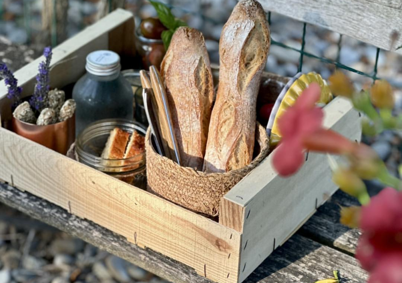 Un pique-nique gourmand avec du pain frais, des boissons et des couverts sur une table en bois.